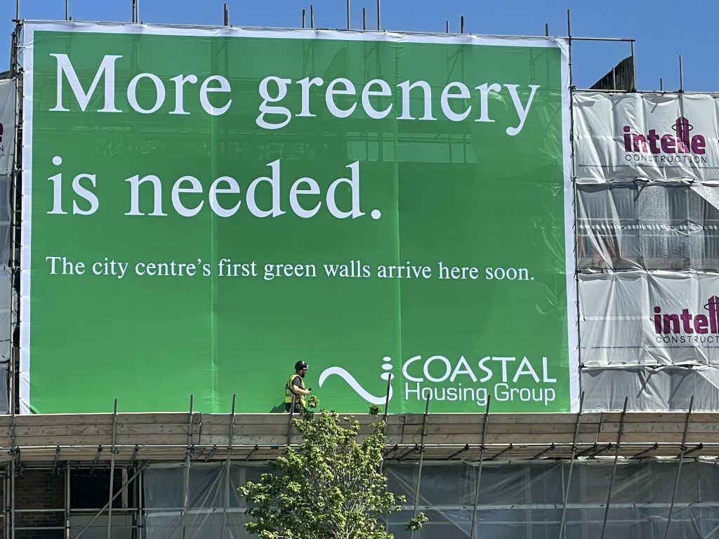 Worker in front of More greenery is needed sign