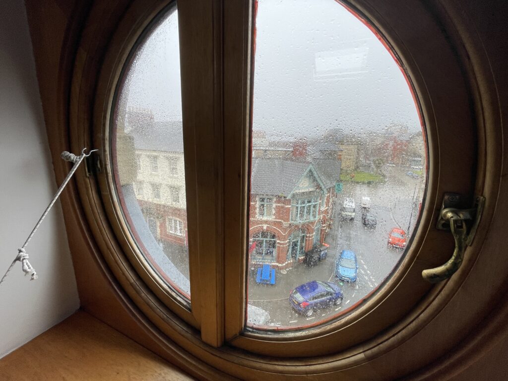 The Queens pub seen through a circular, wooden, upper floor window